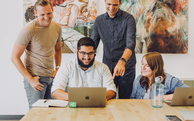 Colleagues gathered around a laptop, smiling during a training session