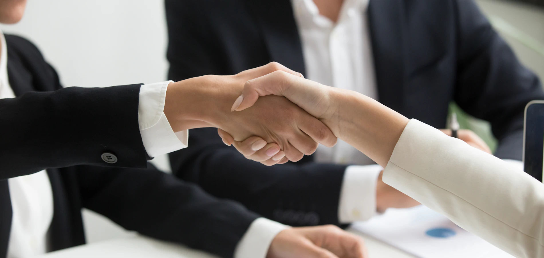 Two professionals shaking hands across a desk