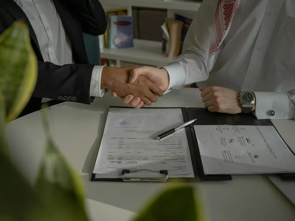 A handshake over signed documents on a desk