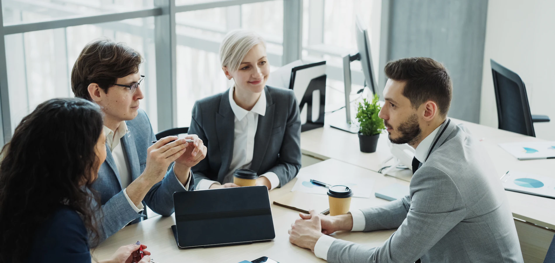 Four professionals in discussion around a meeting table
